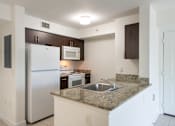 Thumbnail 9 of 33 - A kitchen with a granite counter top and stainless steel appliances.