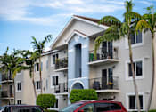 Thumbnail 1 of 23 - A row of apartment buildings with balconies and palm trees in front.