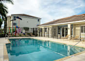 Thumbnail 13 of 23 - A swimming pool in front of a house with a playground.