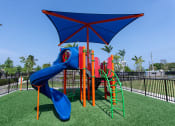Thumbnail 20 of 36 - a playground with a swing set and a blue umbrella