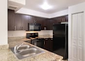 Thumbnail 4 of 23 - A kitchen with a black refrigerator and stove.