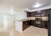 Thumbnail 2 of 23 - A kitchen with brown cabinets and black appliances.
