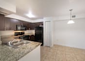 Thumbnail 6 of 23 - A kitchen with granite countertops and a black refrigerator.