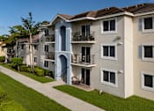 Thumbnail 12 of 23 - A row of apartment buildings with balconies and a clear blue sky.
