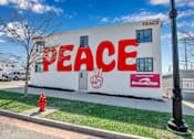 Thumbnail 2 of 7 - A white building with the word "PEACE" written on it in red.