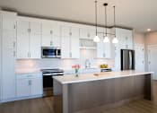 Thumbnail 18 of 52 - A modern kitchen with white cabinets and a central island.