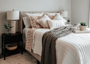 Thumbnail 11 of 52 - A bed with a white comforter and a grey throw is in the image.