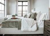 Thumbnail 2 of 52 - A bedroom with a bed covered in a green and white comforter.