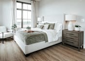 Thumbnail 10 of 52 - A bedroom with a large bed, a chair, and a nightstand.