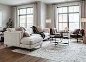 Thumbnail 4 of 52 - A modern living room with a large sofa, a coffee table, and a rug.
