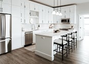 Thumbnail 3 of 52 - A modern kitchen with a white color scheme and stainless steel appliances.