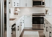 Thumbnail 8 of 52 - A modern kitchen with white cabinets and stainless steel appliances.