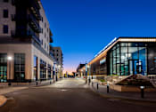 Thumbnail 50 of 52 - A city street at dusk with buildings on either side and a clear sky.