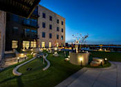 Thumbnail 44 of 52 - A modern building with a well-lit outdoor area at dusk.