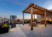 Thumbnail 38 of 52 - A wooden pergola is situated on a rooftop patio with tables and chairs.