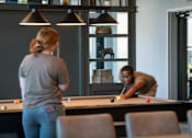 Thumbnail 33 of 52 - A man and a woman playing pool in a room.