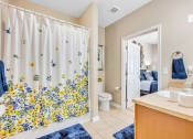 Thumbnail 8 of 26 - a bathroom with a shower curtain and a sink and a toilet