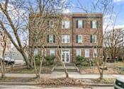 Thumbnail 1 of 34 - A red brick building with a white door and windows. at Shipyard Shores Apartments, Newport News, VA, 23607