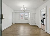 Thumbnail 3 of 34 - A large empty room with a chandelier and a kitchen in the background. at Shipyard Shores Apartments, Newport News, 23607