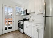 Thumbnail 7 of 34 - A kitchen with white cabinets and a stainless steel refrigerator at Shipyard Shores Apartments, Virginia, 23607
