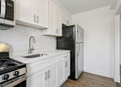 Thumbnail 8 of 34 - A black refrigerator is in a kitchen with white cabinets at Shipyard Shores Apartments, Newport News, VA, 23607