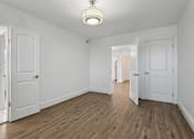 Thumbnail 11 of 34 - A room with white walls and wooden floors with two doors at Shipyard Shores Apartments, Newport News, Virginia