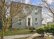 Thumbnail 18 of 34 - A grey house with a front yard and a bare tree at Shipyard Shores Apartments, Newport News, Virginia