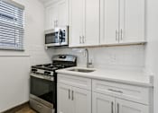 Thumbnail 24 of 34 - A kitchen with white cabinets and a black stove top oven at Shipyard Shores Apartments, Newport News, 23607