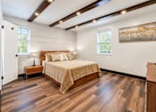 Thumbnail 9 of 10 - A bedroom with a large bed and wooden floors.