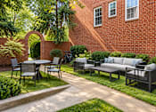 Thumbnail 7 of 10 - A black patio set is on a concrete slab in front of a red brick house.