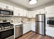 Thumbnail 10 of 10 - A modern kitchen with white cabinets and stainless steel appliances.