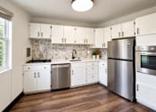 Thumbnail 8 of 10 - A kitchen with white cabinets and a stainless steel refrigerator.