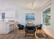 Thumbnail 3 of 30 - a dining room with a glass table and chairs and a kitchen with a large window