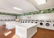 Thumbnail 18 of 23 - A laundry room with a white counter and washing machines at The Aspens Fairhaven, Santa Ana, 92705