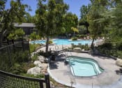 Thumbnail 22 of 30 - a pool and spa at an apartment community with trees
