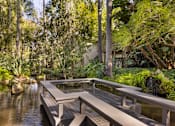 Thumbnail 41 of 42 - A wooden walkway over a body of water surrounded by greenery at The Aspens South Coast, California, 92504