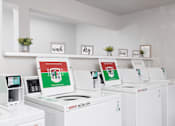 Thumbnail 6 of 8 - A row of Washing machines are lined up in a laundromat.