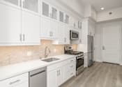 Thumbnail 24 of 35 - a white kitchen with stainless steel appliances and white cabinets