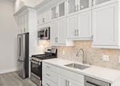 Thumbnail 19 of 35 - a white kitchen with stainless steel appliances and white cabinets