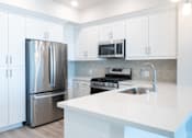 Thumbnail 33 of 88 - A modern kitchen with a stainless steel refrigerator and white cabinets.