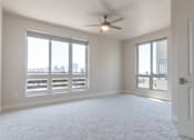 Thumbnail 27 of 88 - A spacious room with a ceiling fan and large windows overlooking a cityscape.