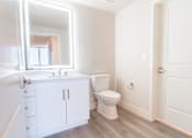 Thumbnail 49 of 88 - A white bathroom with a toilet, sink, and mirror.