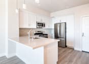 Thumbnail 46 of 88 - A modern kitchen with a stainless steel refrigerator and white cabinets.
