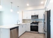 Thumbnail 48 of 88 - A modern kitchen with white cabinets and stainless steel appliances.