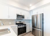 Thumbnail 44 of 88 - A modern kitchen with a stainless steel refrigerator, microwave, and oven.