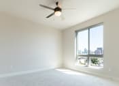 Thumbnail 41 of 88 - A room with a ceiling fan and a large window overlooking a cityscape.
