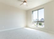 Thumbnail 55 of 88 - A room with a ceiling fan and a large window overlooking a cityscape.