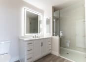 Thumbnail 58 of 88 - A white bathroom with a sink, mirror, and shower.