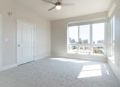 Thumbnail 54 of 88 - A room with a ceiling fan and large windows overlooking a cityscape.