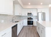 Thumbnail 37 of 88 - A modern kitchen with white cabinets and stainless steel appliances.
